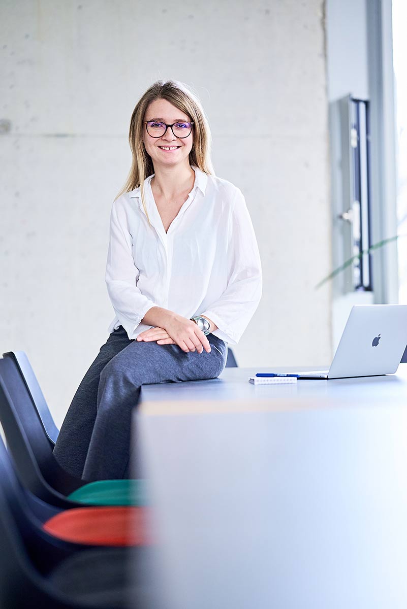 Lynn Schneg sitzt auf einem Tisch, neben ihr ein Notebook